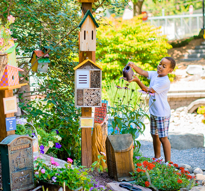 Young boy in Story Garden watering plant