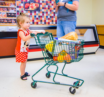 Young girl in Weis Market exhibit pushing shopping cart